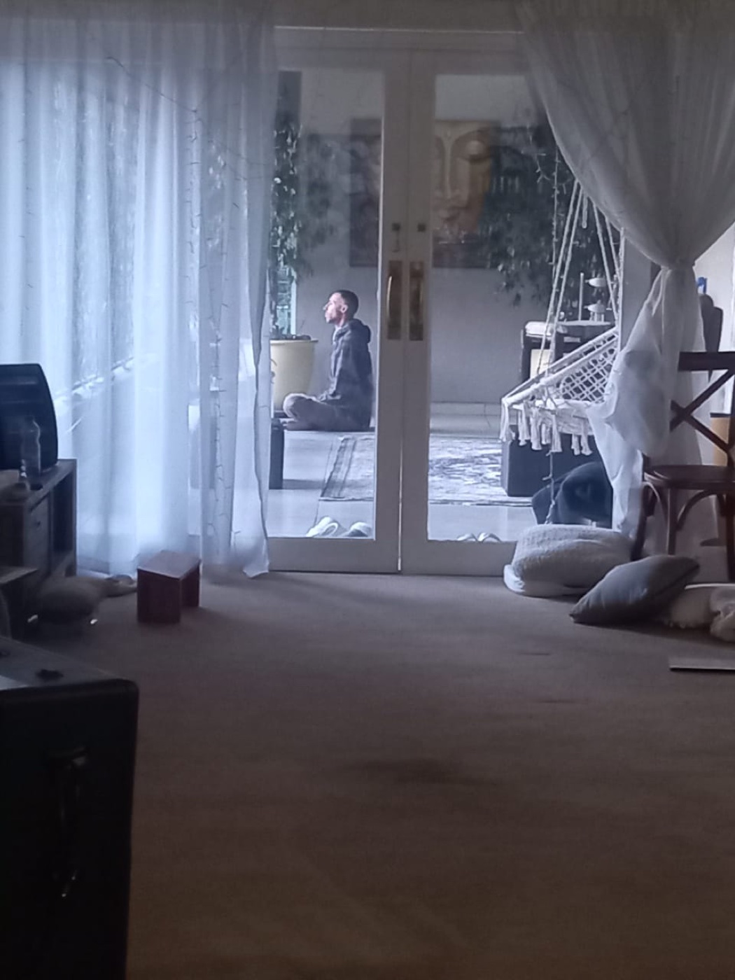 A retreat participant meditating beyond an open doorway.