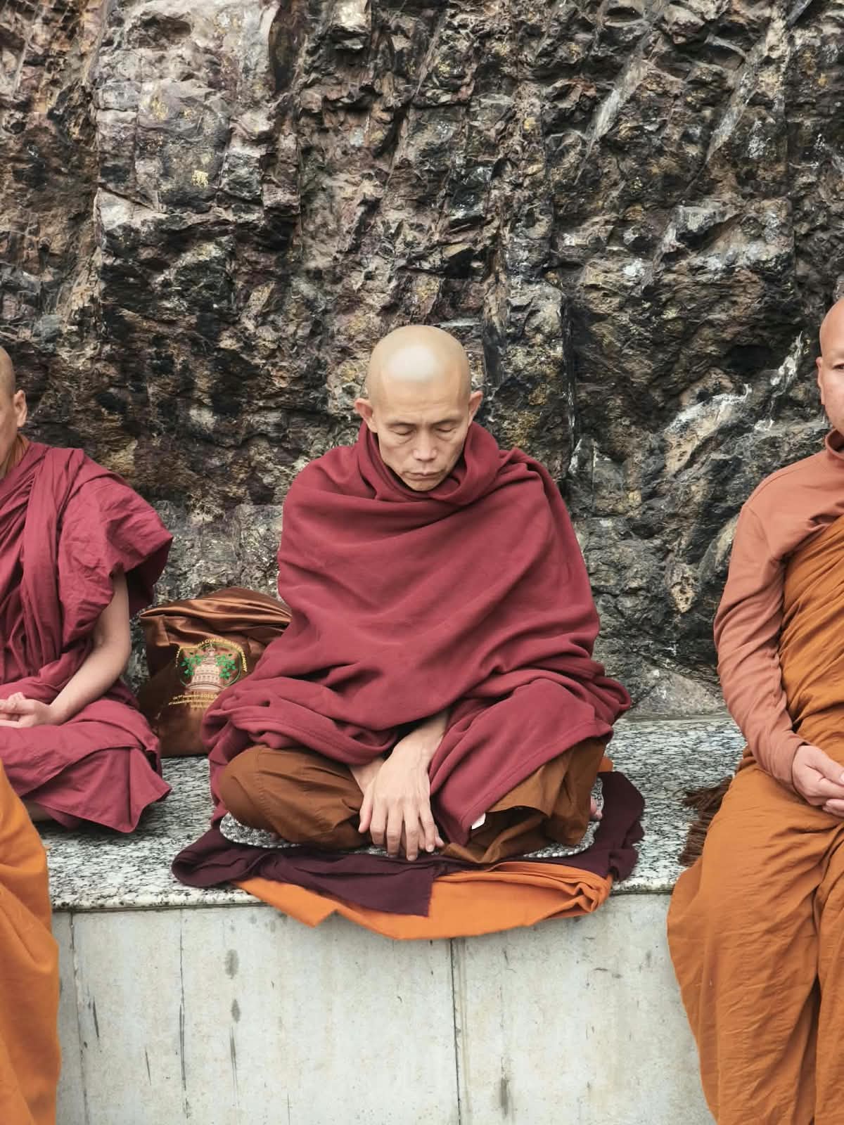 Sayadaw Ashin Ottamathara seated with other monastics before a stone wall.